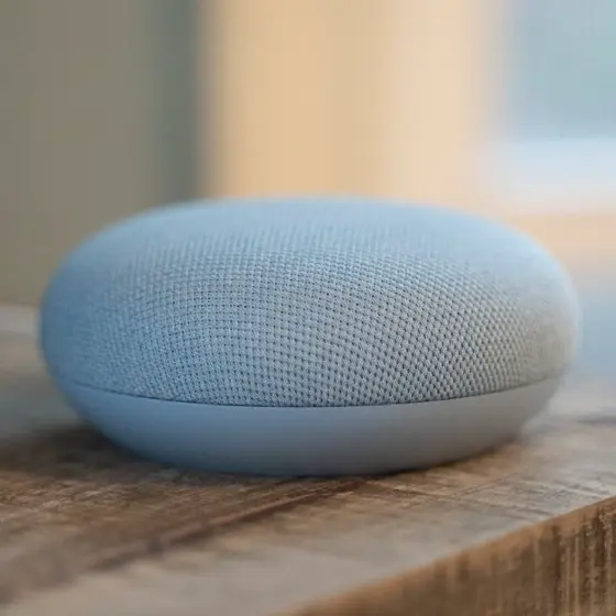 木製テーブルに置かれた水色のGoogle Nest Mini