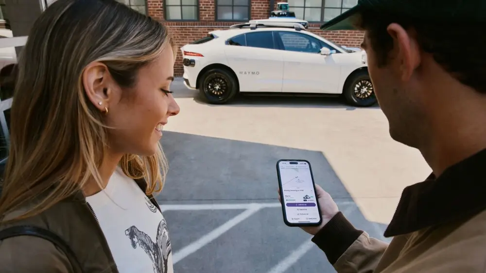 Waymoの自動運転車の前でLyftアプリの配車画面を確認する利用者