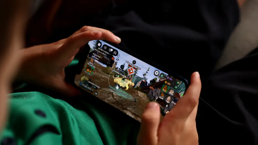 スマートフォンの画面でゲームアプリを操作する手元