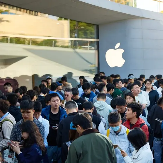 Appleストアの外観とAppleロゴの看板の前に、スマートフォンを手にした多くの人々が列をなして並んでいる様子を写した写真